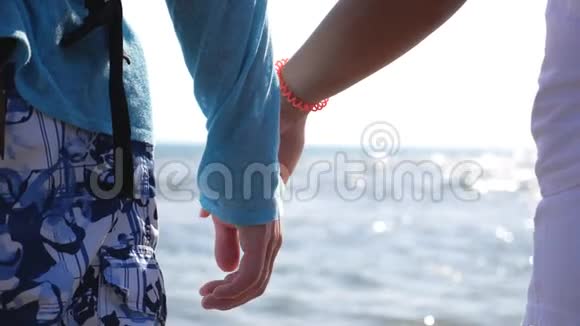 年轻的一对恋人牵着手站在海上调情几个旅行者视频的预览图