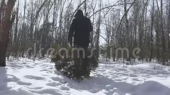 在平安夜和新年之前一个带着斧头的人把树砍倒回家人走在雪地里概念视频的预览图