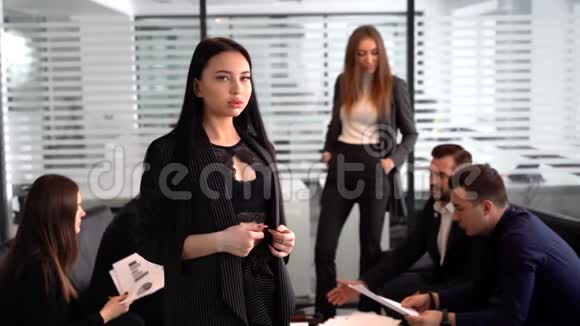 办公室里微笑的女商人双手交叉自信的表情其他员工在办公室开会视频的预览图