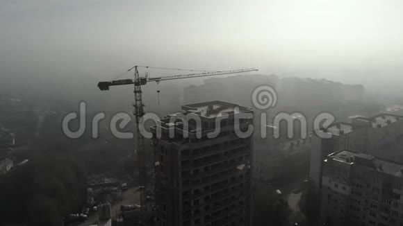 鸟瞰站在居民楼旁雾中的塔吊飞过工地无人机视频的预览图