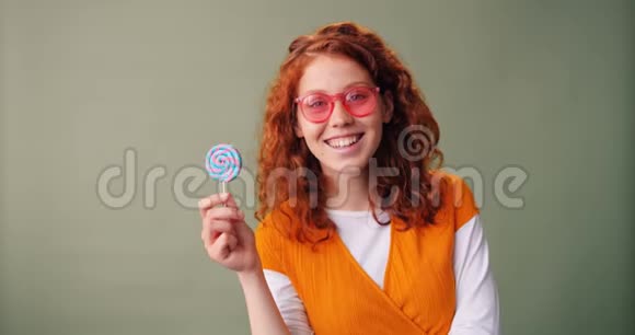 戴着墨镜拿着棒棒糖微笑的快乐少女视频的预览图