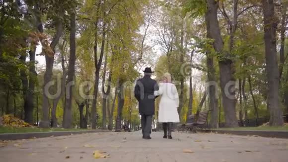 一对成熟的白种夫妇在秋日公园散步聊天的背景穿黑衣服的成熟男人和他的妻子视频的预览图