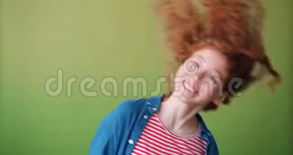 年轻漂亮的女孩在绿色背景下挥舞着卷发视频的预览图