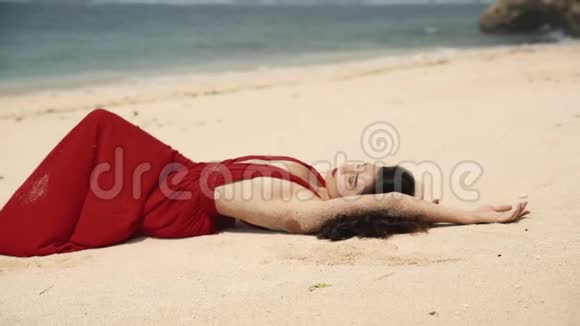 时尚美丽的性感女人黑发优雅的红色连衣裙躺在海滩上美旅游时尚理念视频的预览图