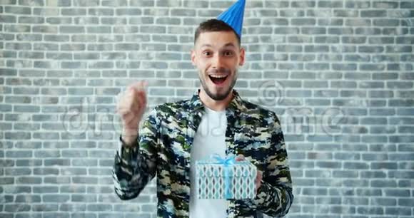 戴着生日礼物摇钱树的派对帽的快乐男人的肖像视频的预览图
