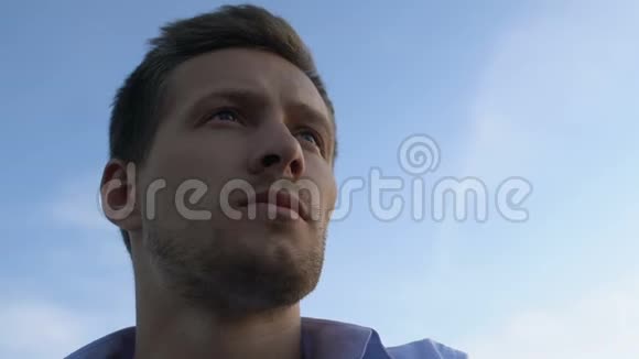 英俊的男人在明亮的天空背景下近距离地思考未来视频的预览图