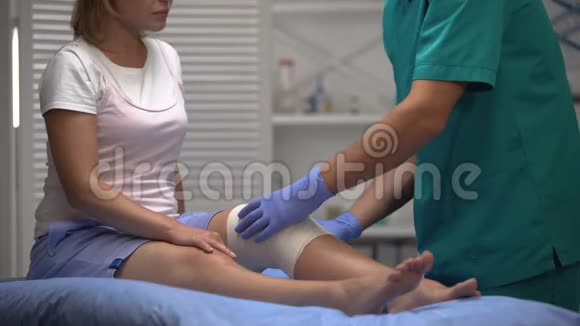 男性医生在女性患者膝盖上应用弹性包裹创伤康复视频的预览图