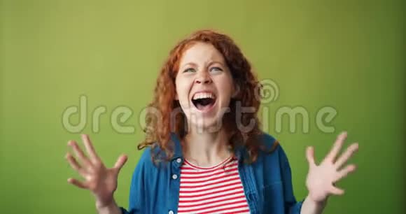 愤怒的少女在绿色背景下尖叫举手的肖像视频的预览图