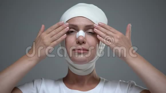 戴头巾的女士在整容后看着她的倒影举起视频的预览图