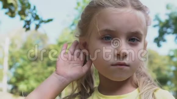 可爱的白种人女孩用手靠近耳朵做听力手势八卦新闻视频的预览图