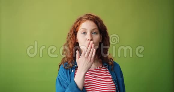 少女在绿色背景下送空气亲吻和眨眼的肖像视频的预览图