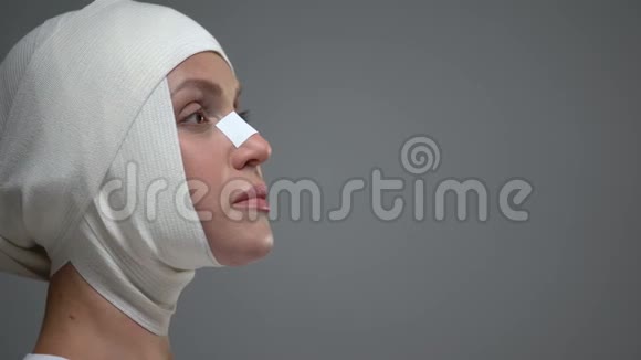 戴头巾的女人站在灰色背景上头骨受伤事故结果视频的预览图