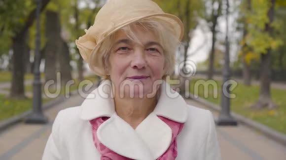 一位白人女性的特写镜头蓝眼睛看着镜头微笑着米黄色紧身衣的成熟女士视频的预览图