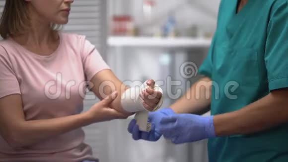 外科医生对女性患者手臂应用弹性包裹创伤后康复视频的预览图