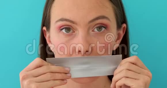 一张年轻女孩的照片她的嘴唇被灰色背景的带子遮住了视频的预览图