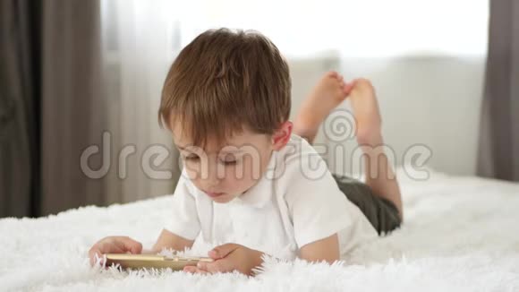 可爱的小男孩用智能手机玩孩子看着智能手机屏幕笑申请视频的预览图