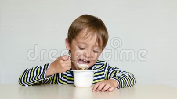 可爱的男孩坐在桌子旁胃口很好吃酸牛奶产品或酸奶婴儿食品生产天然和视频的预览图