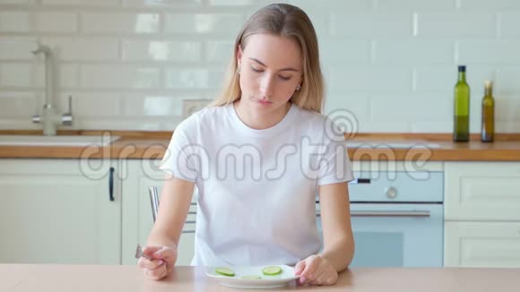 沮丧的节食女人在盘子里吃黄瓜视频的预览图