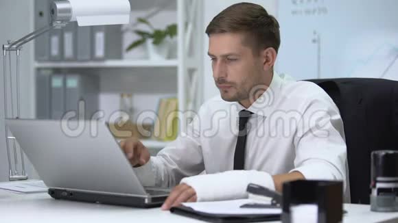 一只手在笔记本电脑上打字手臂骨折的工作狂视频的预览图