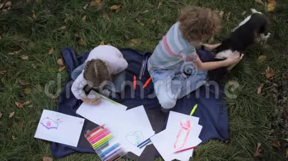 两个快乐的孩子男孩和女孩躺在草地上夏天公园里带着狗孩子们的兄弟姐妹会读书画画玩游戏视频的预览图