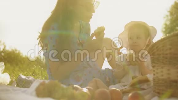 宝贝和妈妈一起在户外吃饭在炎热的夏日野餐视频的预览图