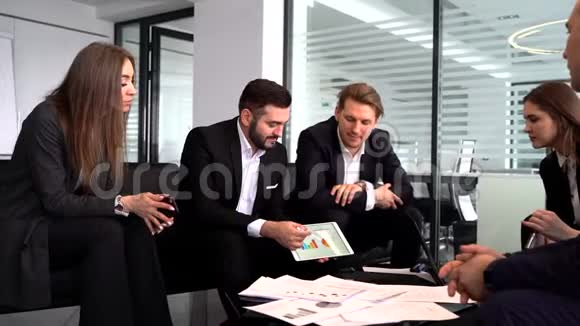 一群三个商人在平板电脑上看到一张图表视频的预览图