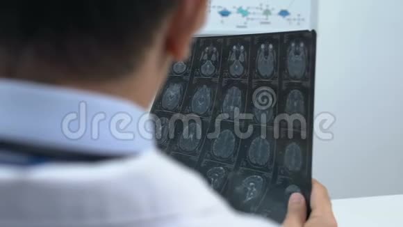 快乐的病人看着良好的核磁共振脑扫描和微笑的医生医疗保健视频的预览图