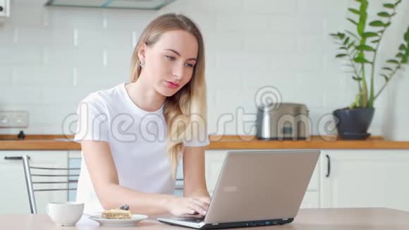 带手提电脑在家吃甜点蛋糕和茶的年轻女性视频的预览图