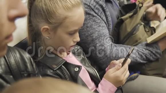 可爱的少女坐在地铁里看着她的手机儿童利用互联网搜索信息视频的预览图