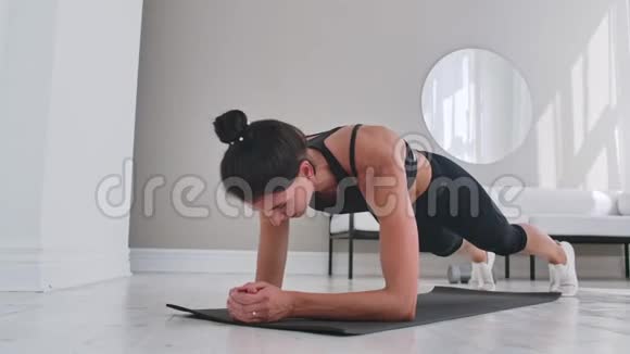专注的女运动员在家里做木板运动客厅视频的预览图