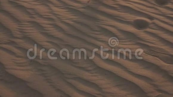 一个穿着白色连衣裙的女人赤脚走在沙漠的沙滩上慢动作视频的预览图