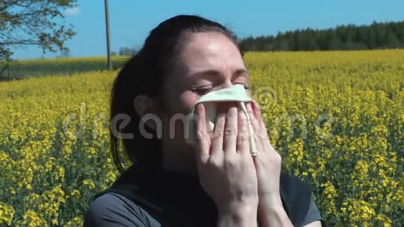 女人在油菜花田里打喷嚏花粉过敏的概念视频的预览图