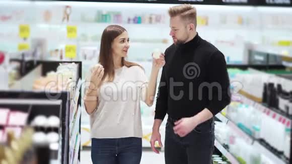 夫妻俩在化妆品店里选择奶油女人打开闻一闻视频的预览图