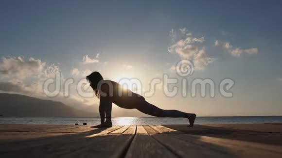 4K一个年轻女孩在日出时缓慢地在海边做瑜伽姿势视频的预览图