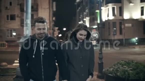 一对夫妇在夜里离开镜头在城市的街道上散步视频的预览图
