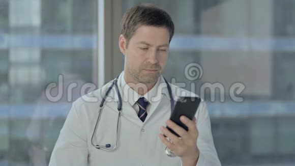 中年医生使用智能手机滚动视频的预览图
