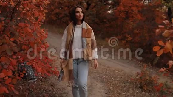 女人享受秋天的日子她走在森林里四周有五颜六色的叶子动作缓慢视频的预览图