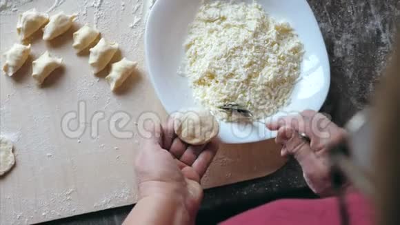 成熟的女性手在家厨房用奶酪包饺子视频的预览图