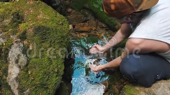 一个年轻的旅行者从山河或春天喝干净的清水视频的预览图