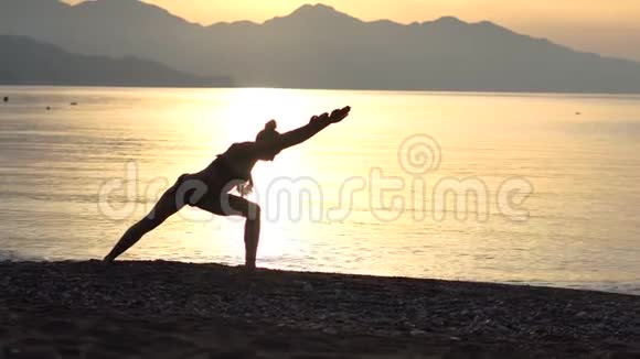 4k女性剪影日出时在海滨做瑜伽体式慢动作视频的预览图
