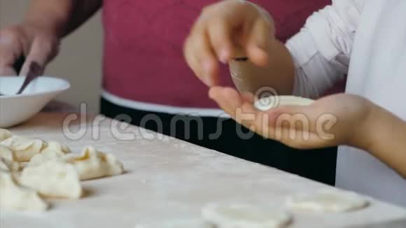祖母带着孙女在家厨房里包着奶酪的饺子视频的预览图