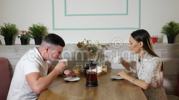 年轻夫妇在咖啡馆的木桌上聊天喝茶视频的预览图