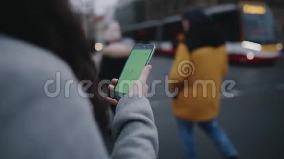 女子手持手机逆着城市道路通行绿色屏幕与共空间铬技术视频的预览图