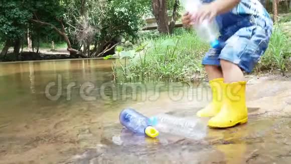 亚洲的小孩子正在公共河边捡垃圾和塑料瓶装在黑色的袋子里环境保护视频的预览图