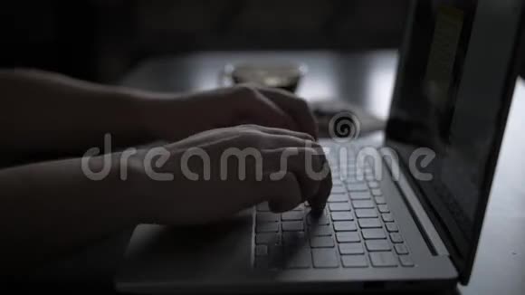 晚上桌旁的一个男人正在靠窗用笔记本电脑工作正在喝咖啡特写镜头视频的预览图