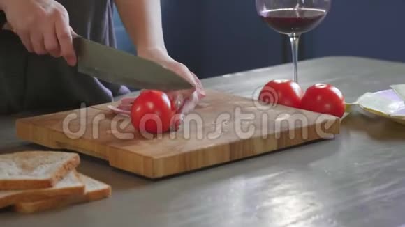 女人在厨房的木板上用锋利的刀把俱乐部三明治切成两半在家里做快餐视频的预览图