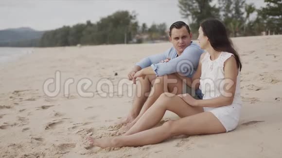 年轻的情侣游客坐在海滩上视频的预览图