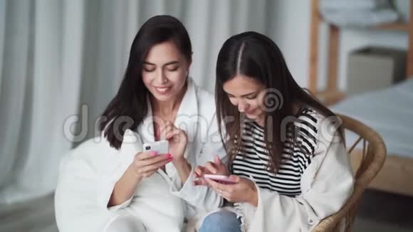 关闭两个女孩在网上购物从银行卡输入数据进入电话视频的预览图