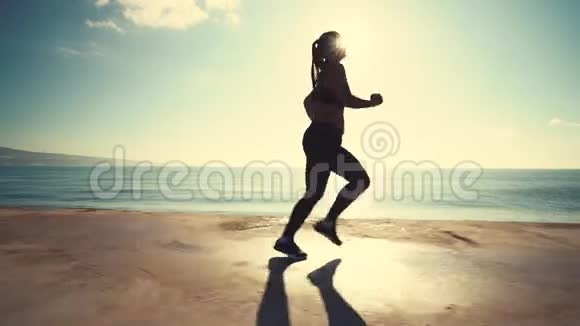 健康的年轻女子在日出的录像中在海边奔跑视频的预览图