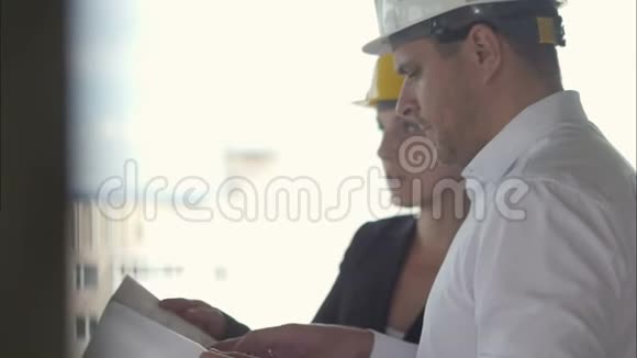 在建筑工地工作时一个有攻击性的商人和一个女商人一起看项目计划视频的预览图